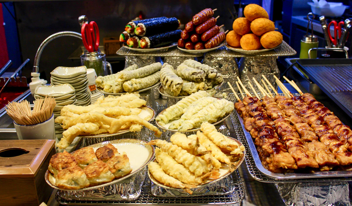 Variedad de comida callejera coreana con brochetas y frituras servidas en un puesto de mercado