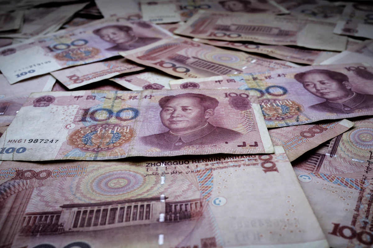 Billetes de 100 yuanes chinos extendidos sobre una mesa como efectivo de reserva para viajar por China