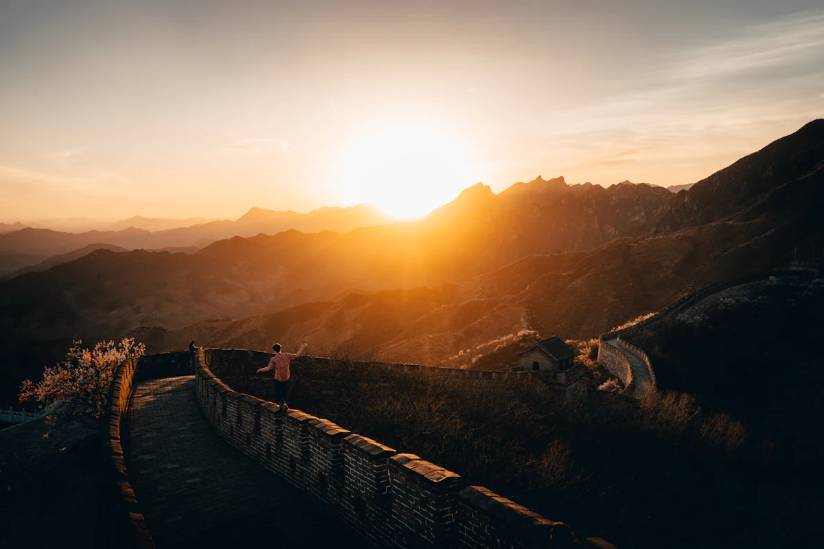 Persona caminando por las almenas de la Gran Muralla China al atardecer