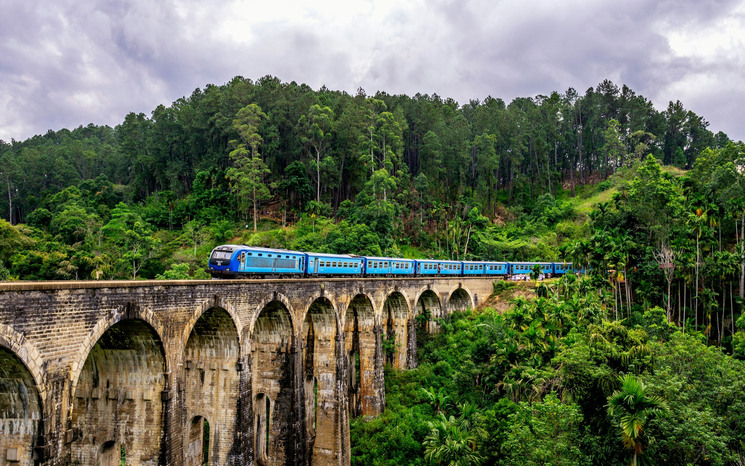 Tren cruzando el Puente de los Nueve Arcos entre plantaciones de té verdes en Ella, Sri Lanka