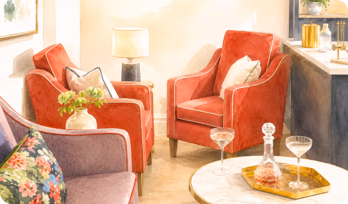 Cozy living room with red armchairs, a purple sofa with floral pillow, and a marble table with drinks.
