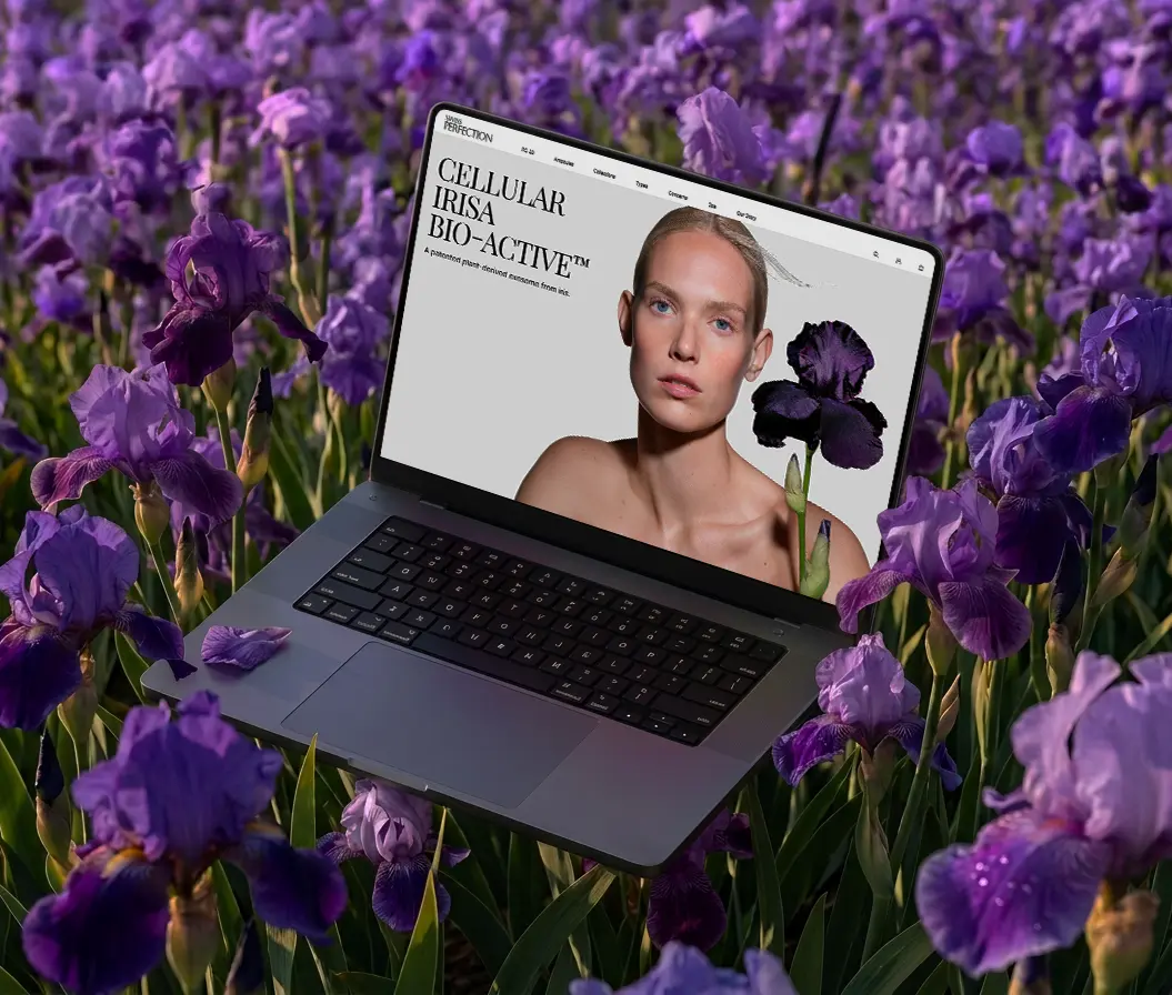 A laptop mockup placed in a field of purple iris flowers, displaying the Swiss Perfection homepage featuring the Cellular Irisa Bio-Active campaign.