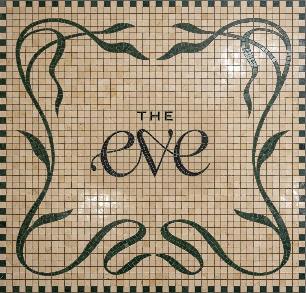 The Eve hotel logo rendered as a decorative mosaic tile floor, featuring the brand's script wordmark surrounded by an ornamental dark green and cream tile pattern.
