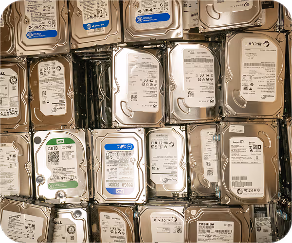 Several used internal hard disk drives stacked closely together in a pile.