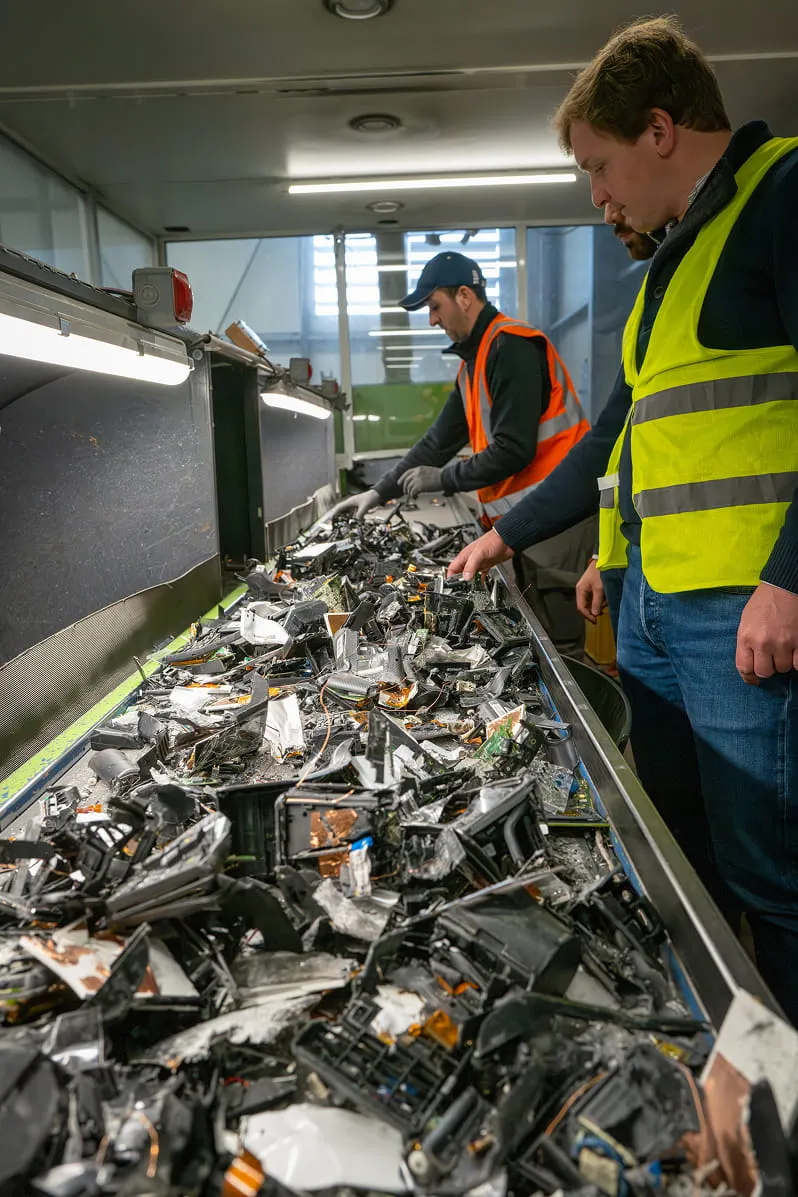Opérateurs Loxy triant des déchets électroniques sur un tapis de tri