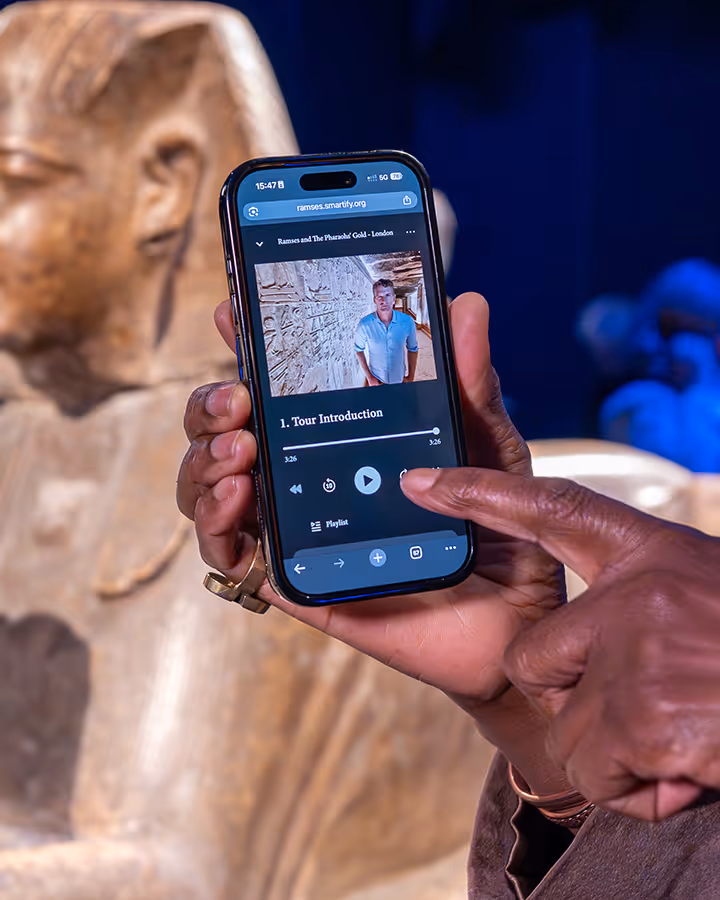 Person holding a phone, using the audio guide for Ramses The Exhibition
