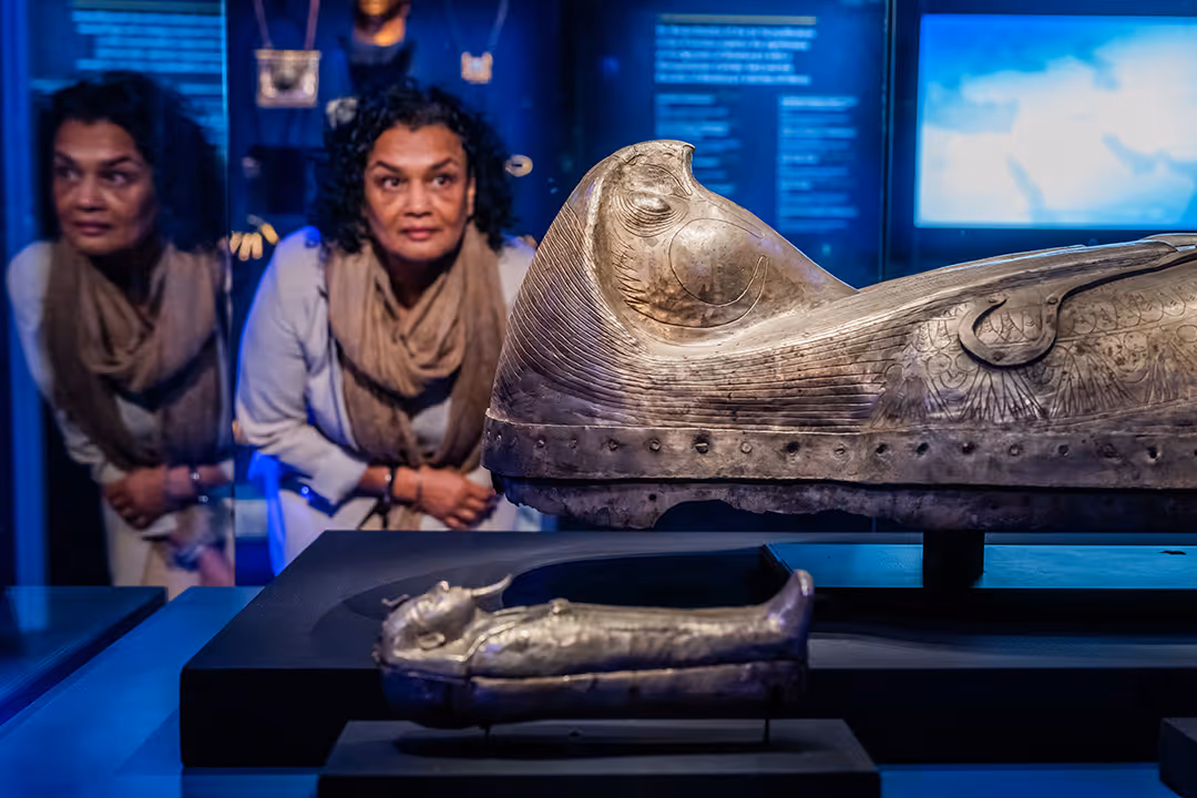 A woman observing the ancient silver coffin on display at Ramses The Exhibition.