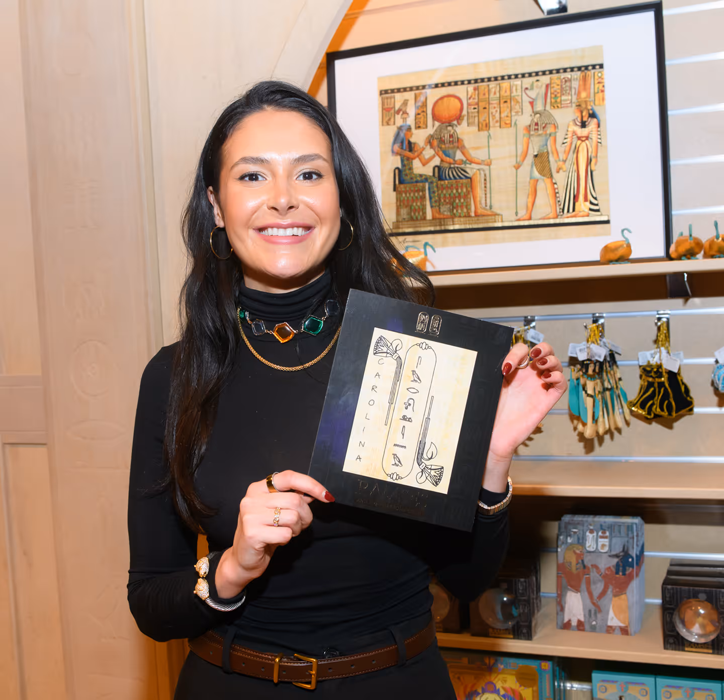 Happy woman holding up a Hieroglyphic of her name from a corporate event.