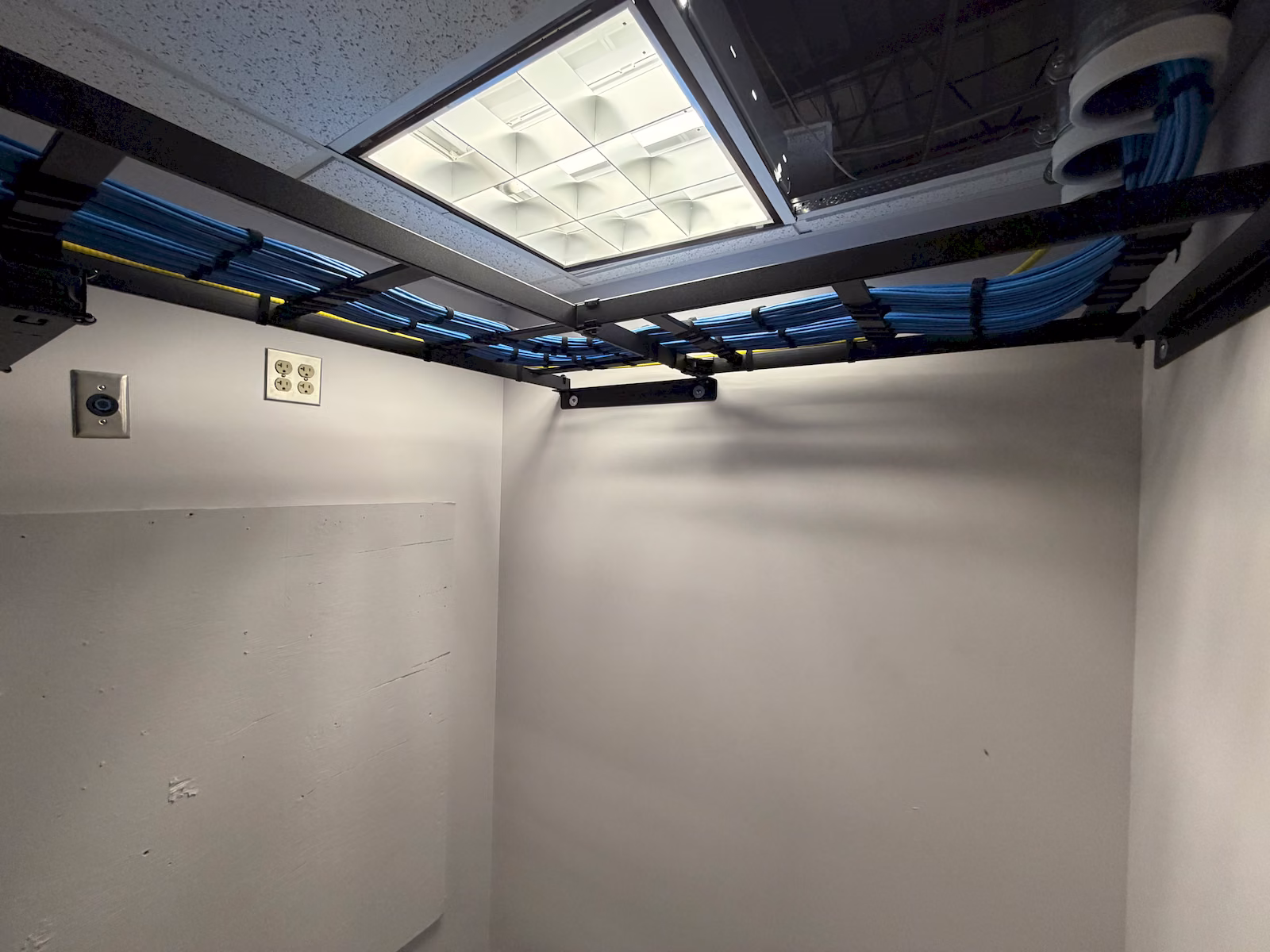 Completed commercial network rack with organized blue patch cables and overhead cable routing.