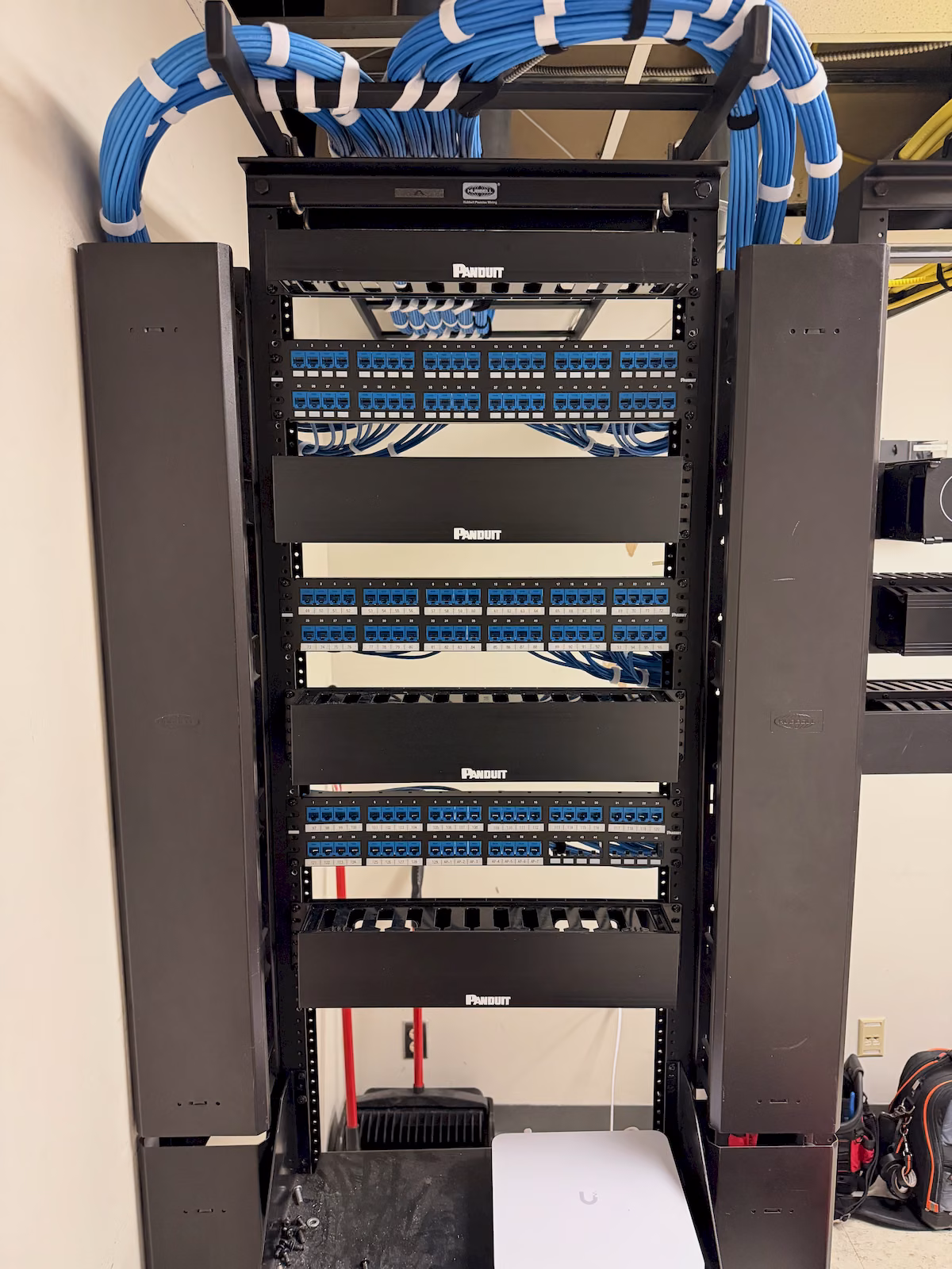Close view of labeled commercial patch panels with neatly routed blue network connections.