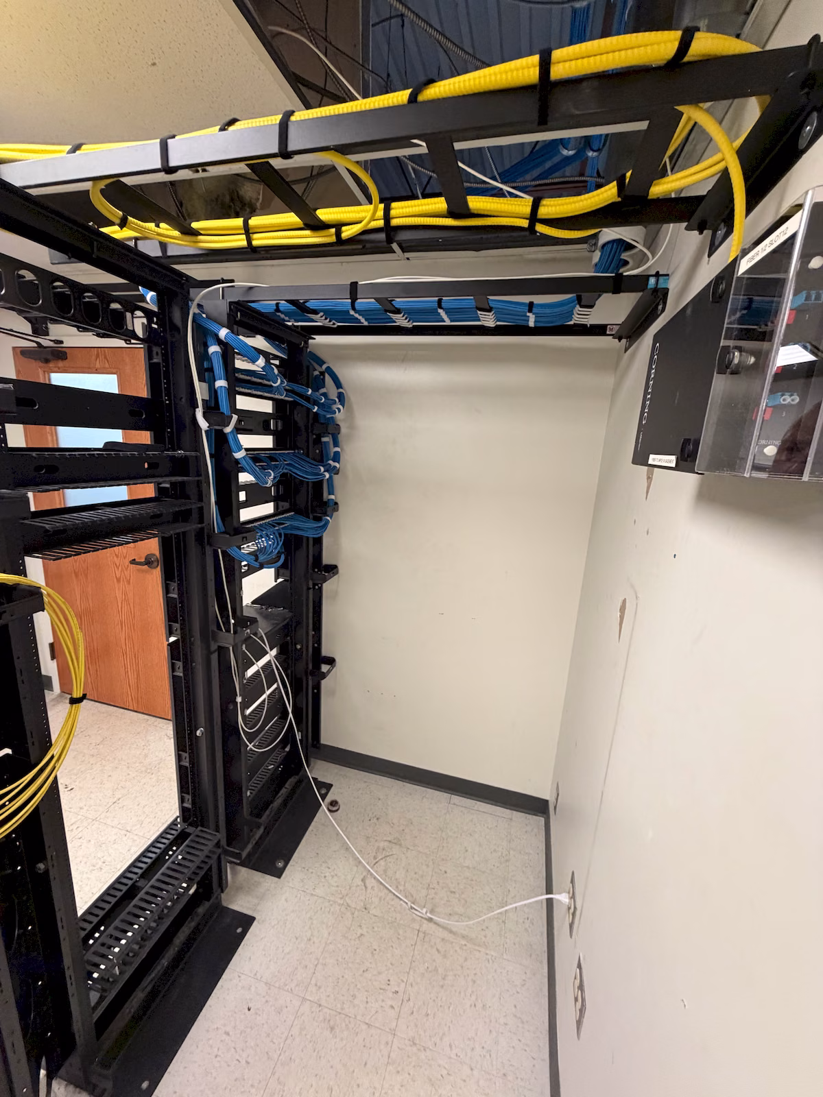 Blue and yellow cabling routed across separate overhead cable pathways above equipment racks.