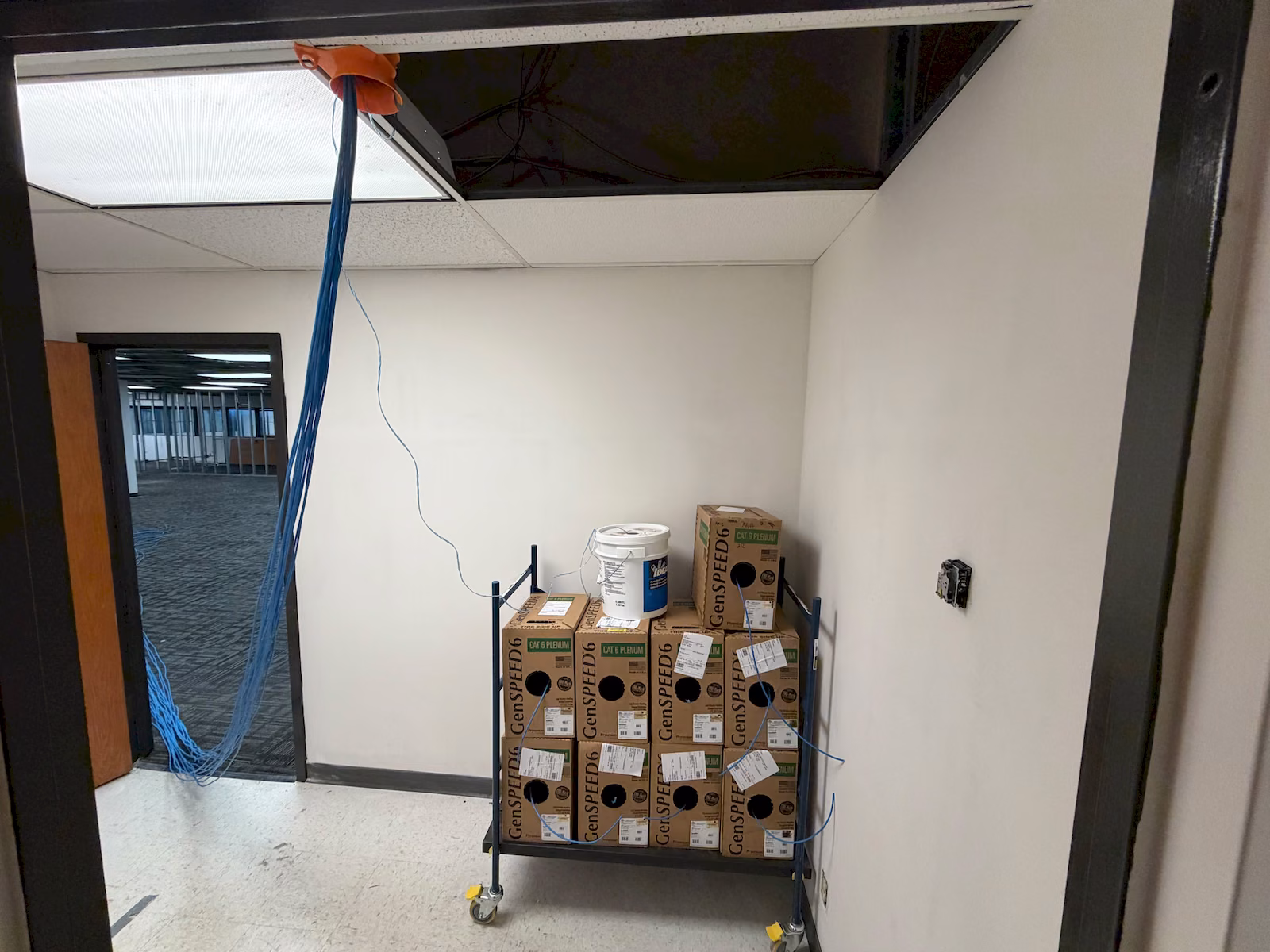 Boxes of Cat 6 plenum cable beside blue cabling pulled through the ceiling during installation.