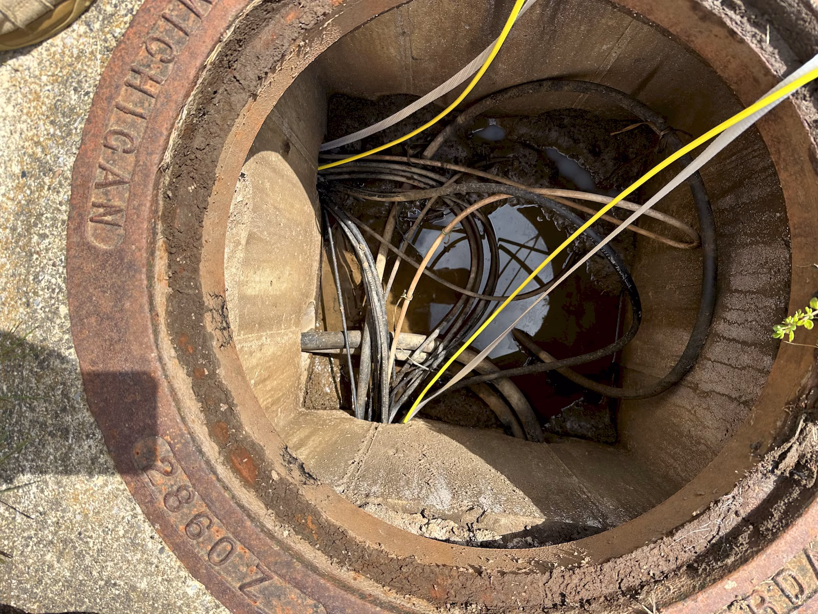 Close view inside an underground communications vault showing fiber cable, pulling tape, and existing cabling.