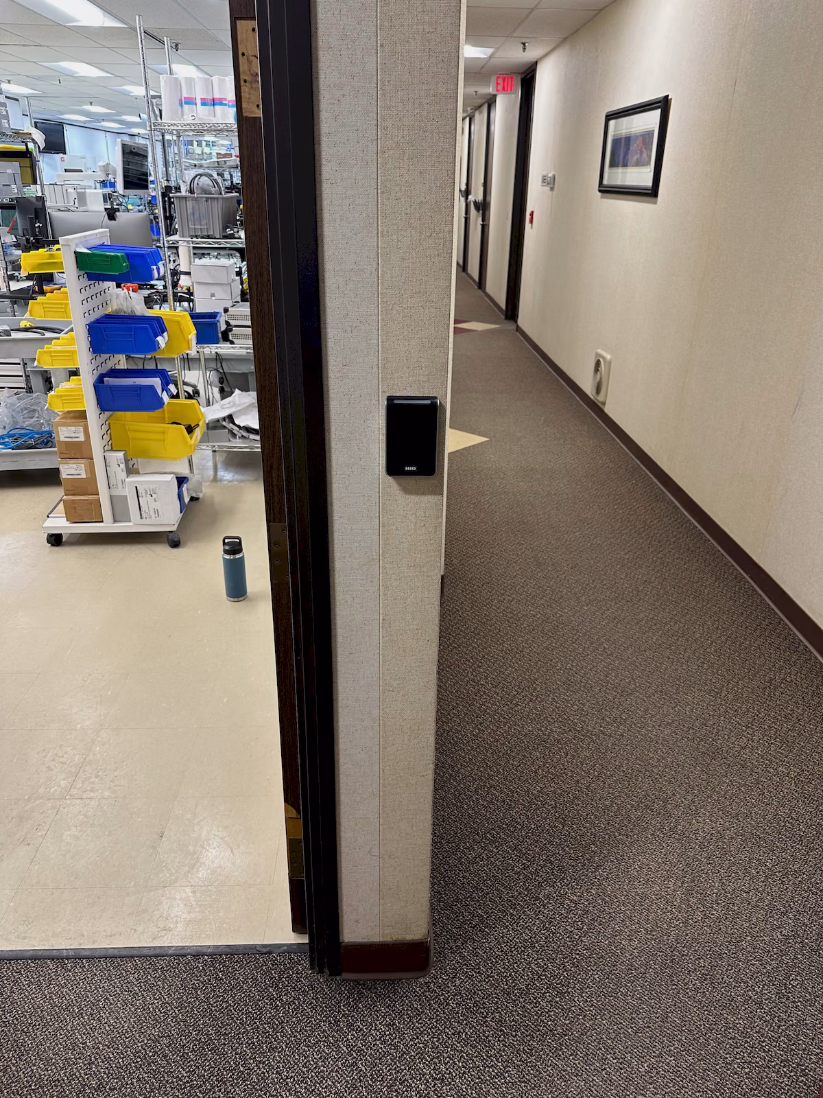Wall-mounted credential reader installed beside an access-controlled commercial doorway.