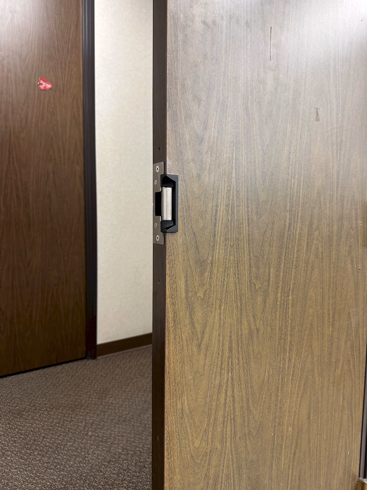 Close view of an electric strike installed in the edge of an existing wood commercial door.