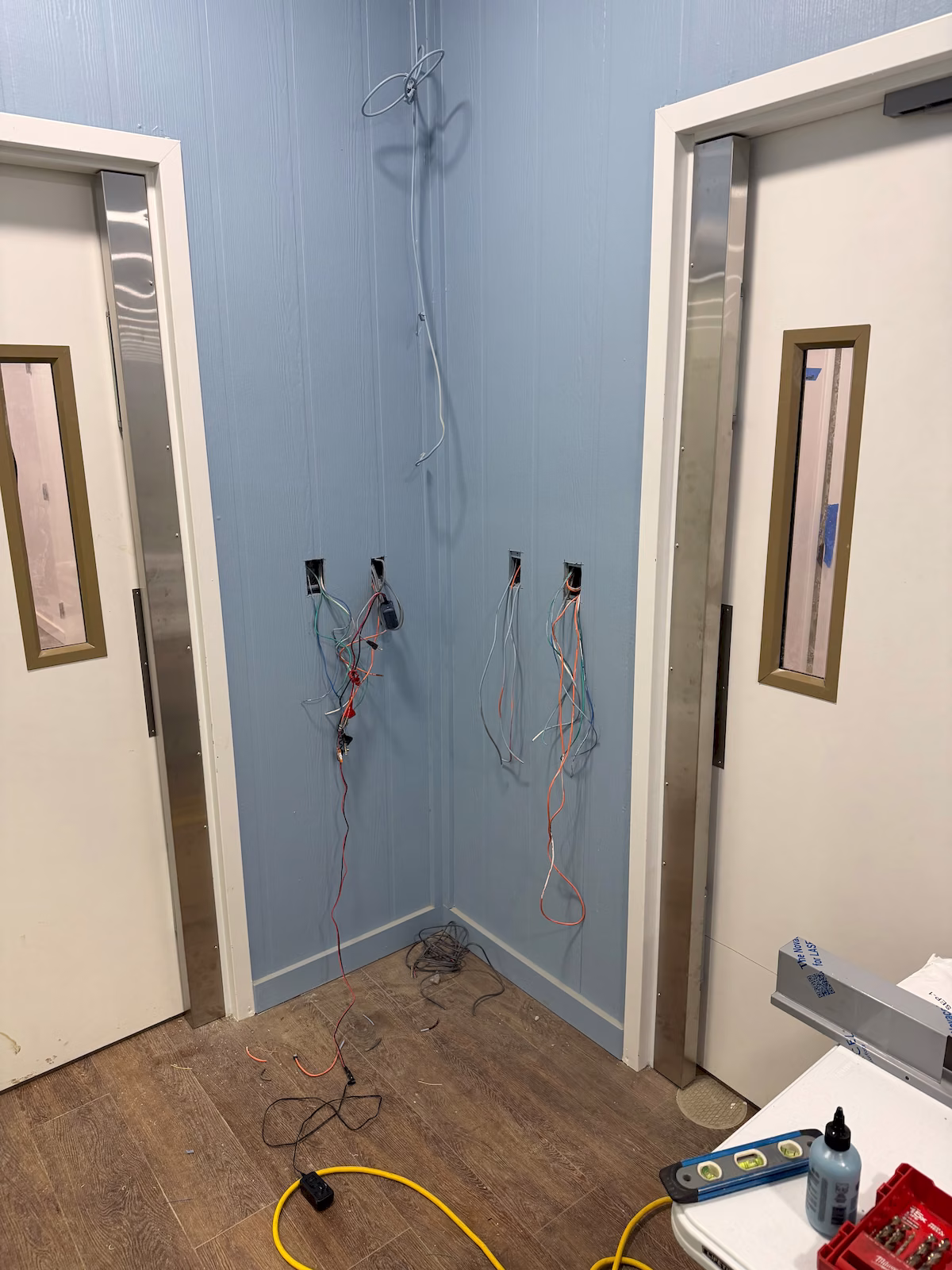 Low-voltage access control wiring exposed between two doors during full-length maglock installation.
