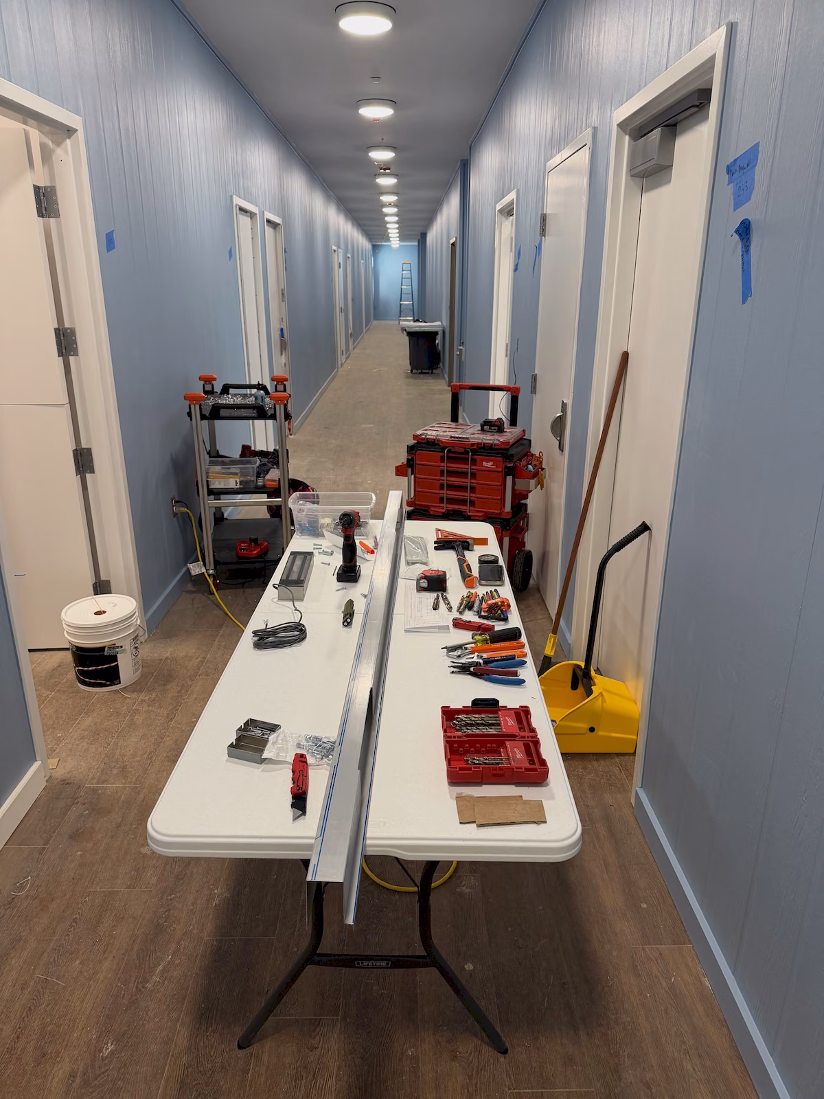 Access control hardware and installation tools staged in a commercial hallway for a multi-door maglock project.