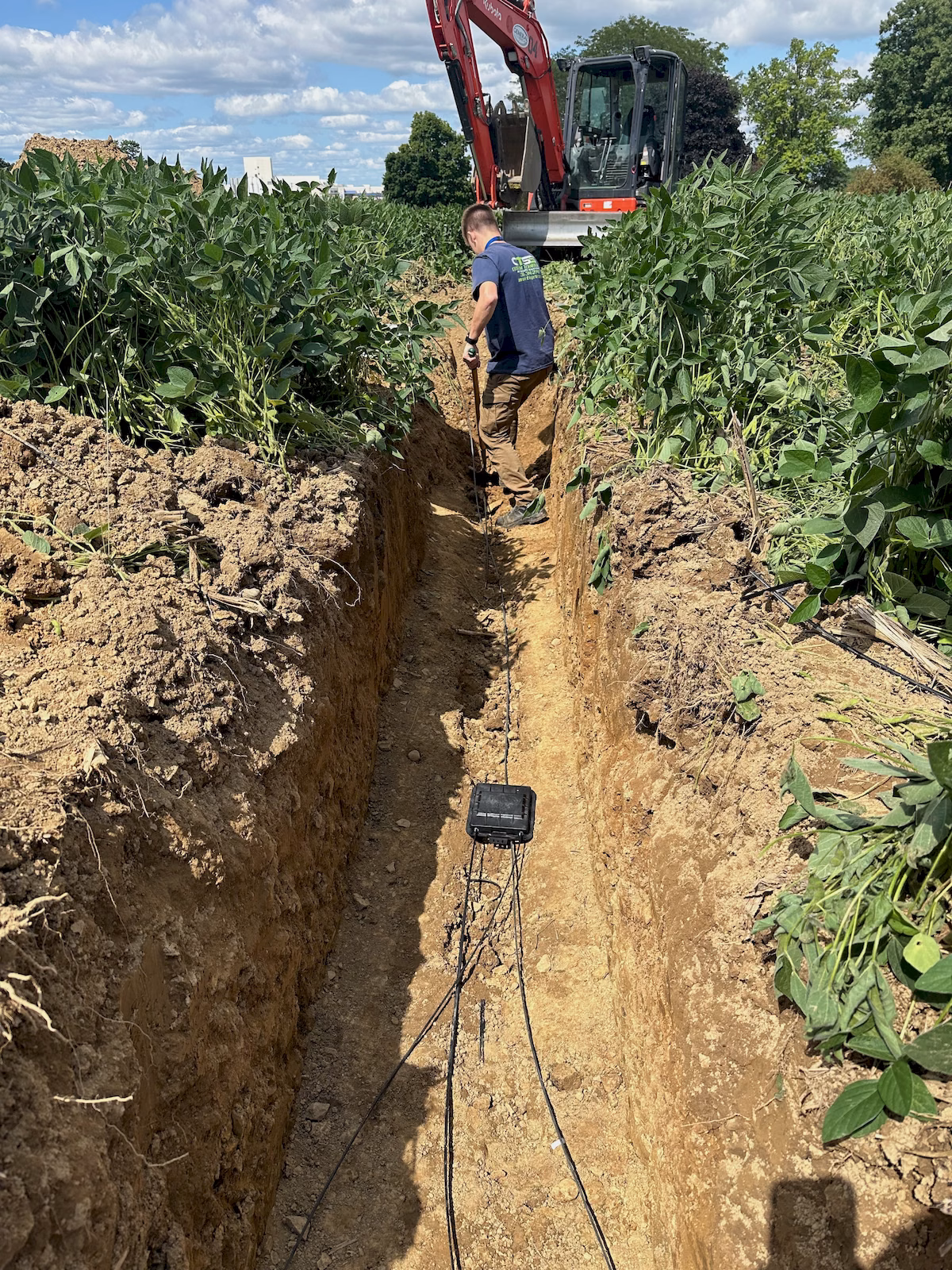 Sealed fiber splice closure and cable runs positioned inside an open underground trench.