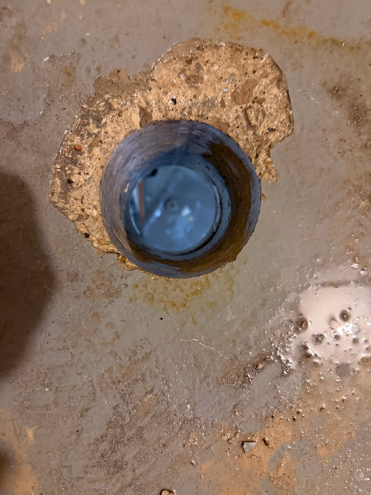 Close view of a finished circular penetration core-drilled through an existing concrete floor.