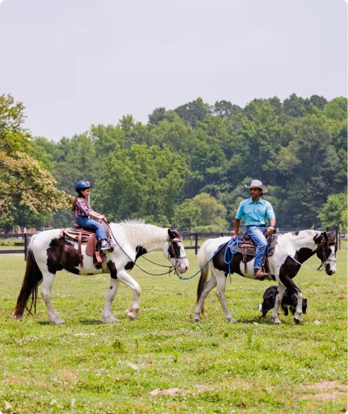 Two riders on paint horses in a green field at Kay's Acres
