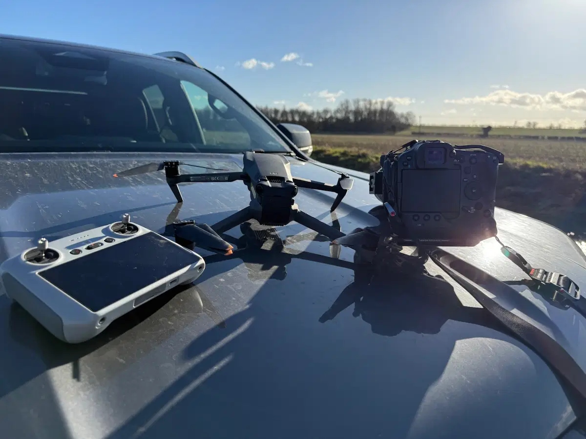 Essential Black Grouse Media field kit displayed on a vehicle bonnet, featuring a drone with controller and DSLR camera