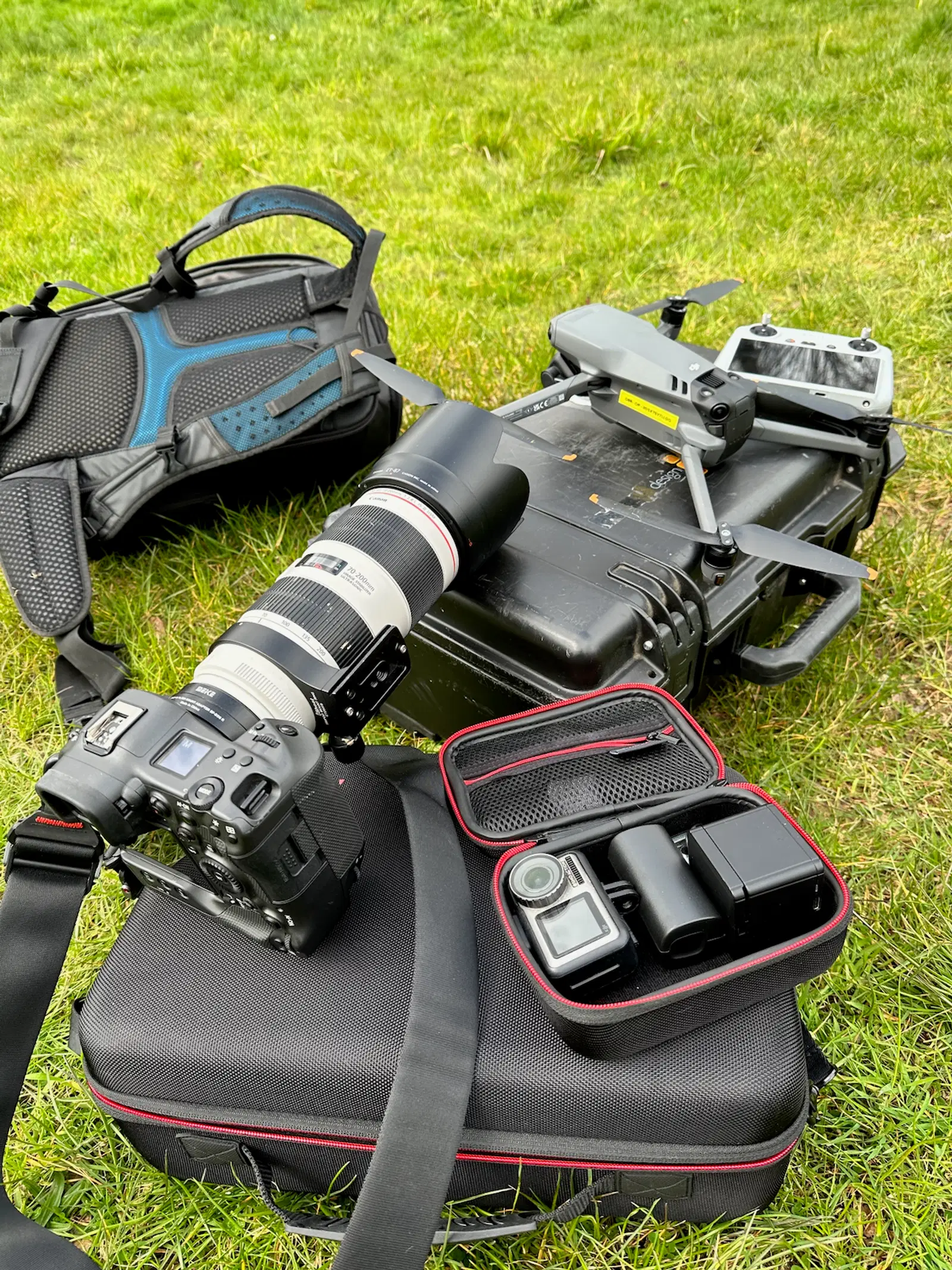 Professional media kit laid out on grass, featuring a drone and cameras