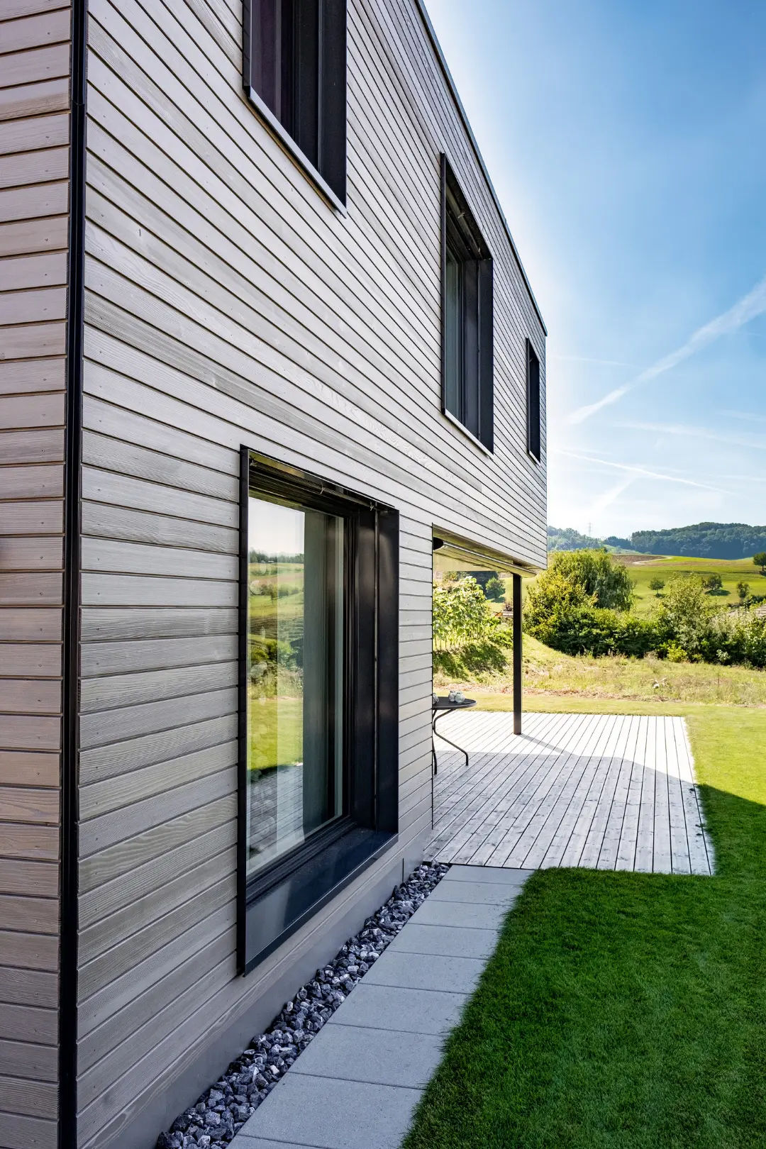 Einfamilienhaus Gansingen – Holzfassade und Terrasse mit Ausblick in die Landschaft
