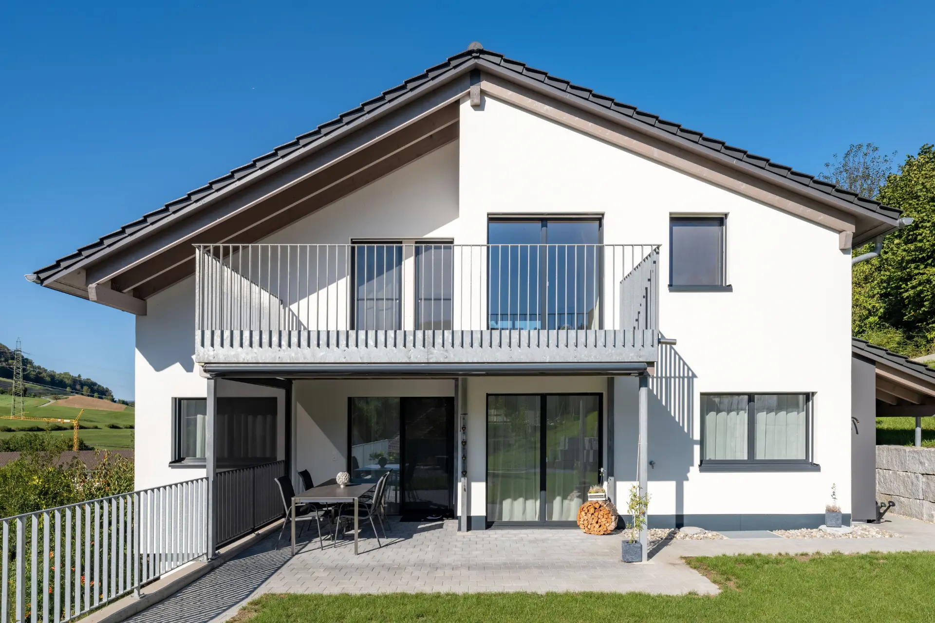 Seitenansicht des Einfamilienhauses in Sulz mit gedeckter Terrasse und Gartenbereich in Hanglage