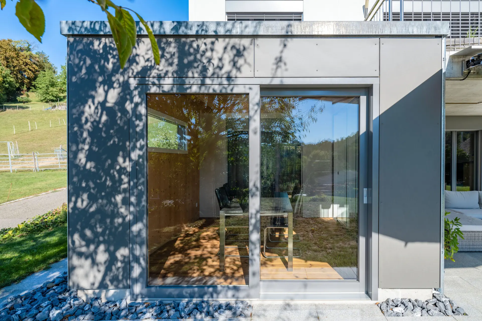 Gartenseitige Ansicht des Wintergartenanbaus in Etzgen mit Vollglas-Schiebwand und Faserzementfassade in Anthrazit.