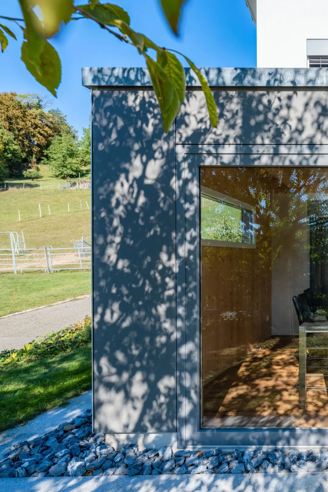 Gartenseitige Ansicht des Wintergartenanbaus in Etzgen mit Vollglas-Schiebwand und Faserzementfassade in Anthrazit.