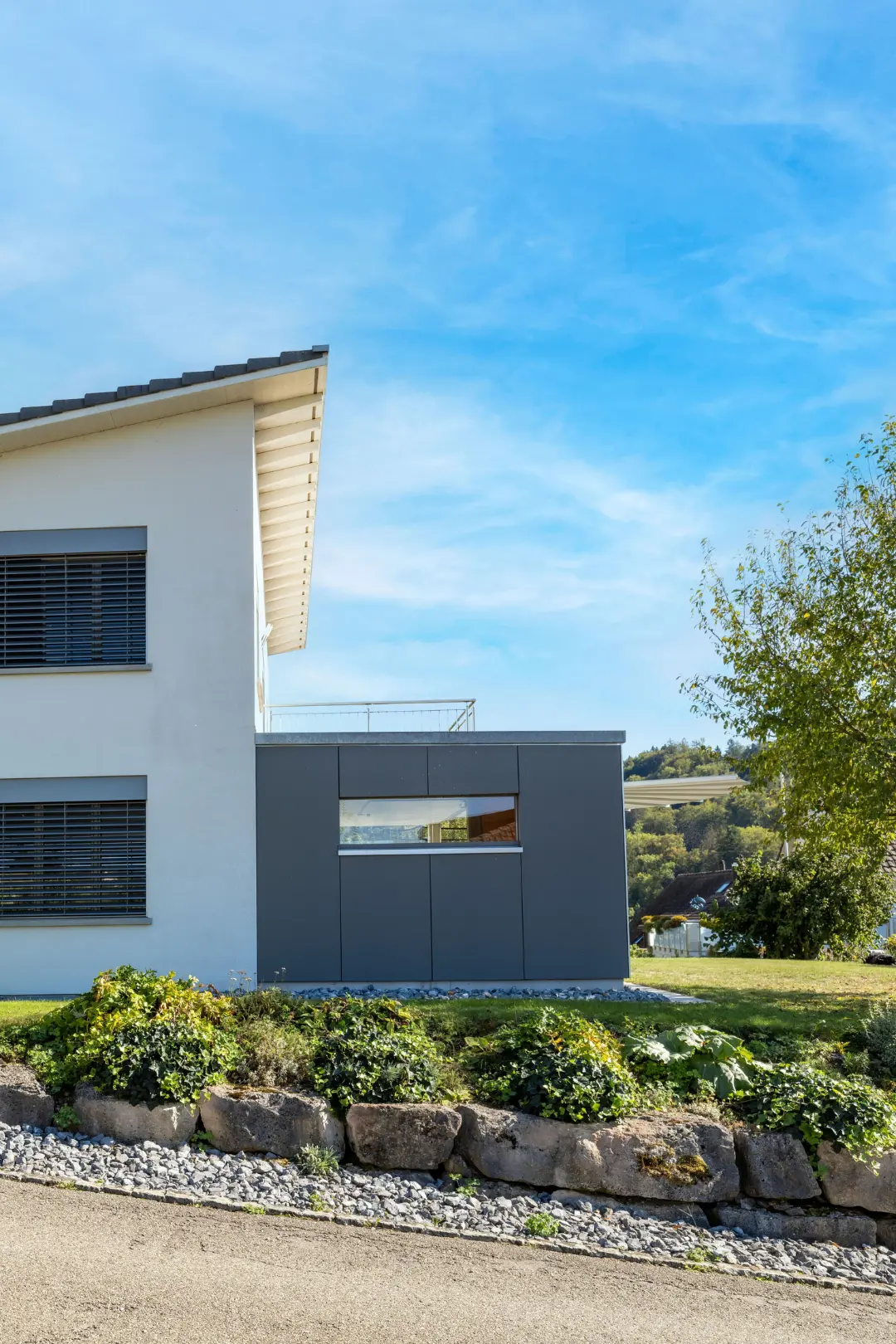 Hausanbau mit dunkler Fassade an bestehendem Einfamilienhaus