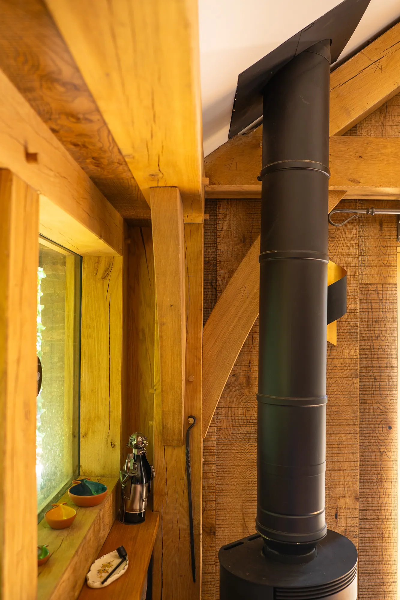 Inside the oak frame extension at Llangattock, the wood burner flue rising between oak posts