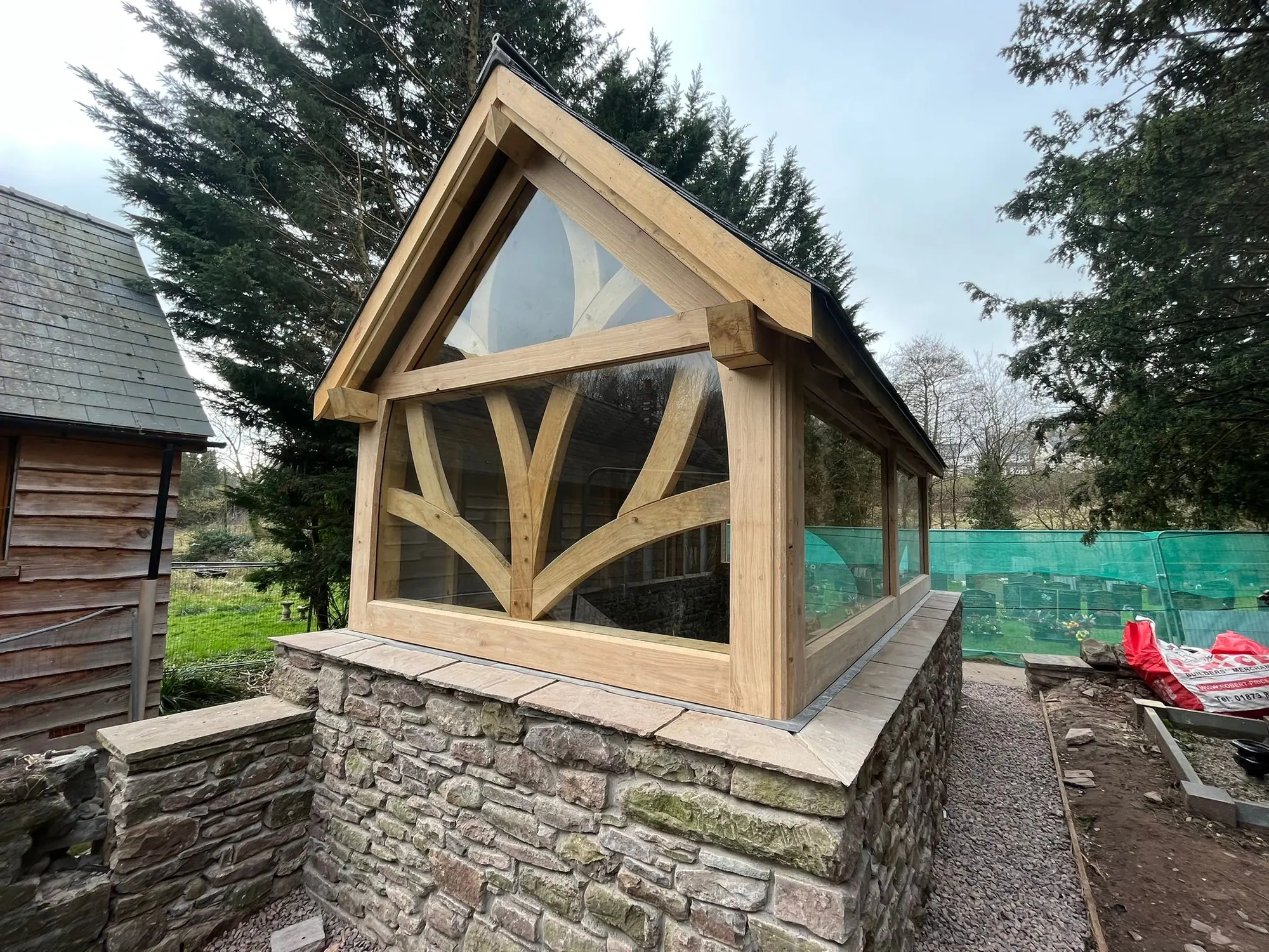 The oak frame chapel of rest at Llantilio Pertholey, a glazed gable on a stone plinth, photographed before the site was cleared