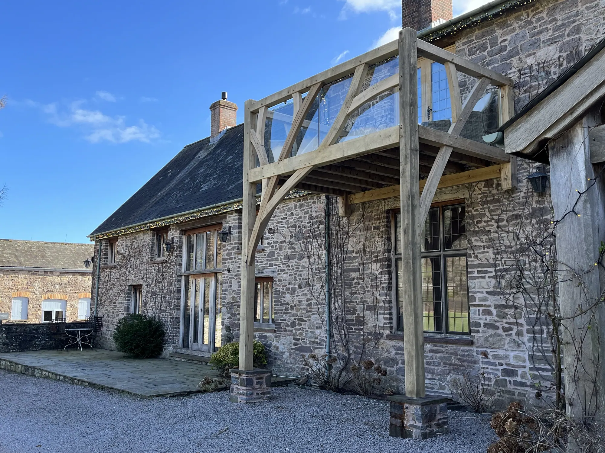 The oak balcony at Duffryn Mawr, carried on two oak posts against the stone house, with a glass balustrade.