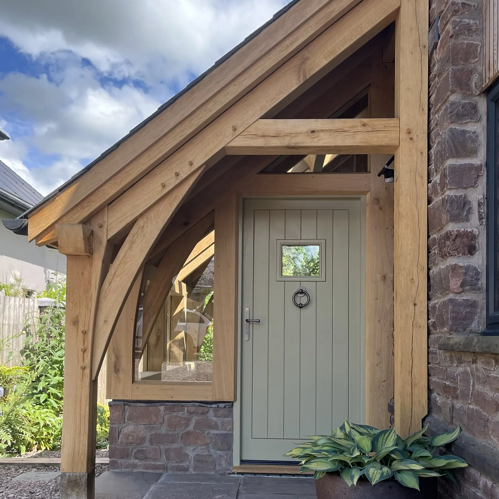 Oak frame porch at Llanvihangel Crucorney with curved oak brace and green front door