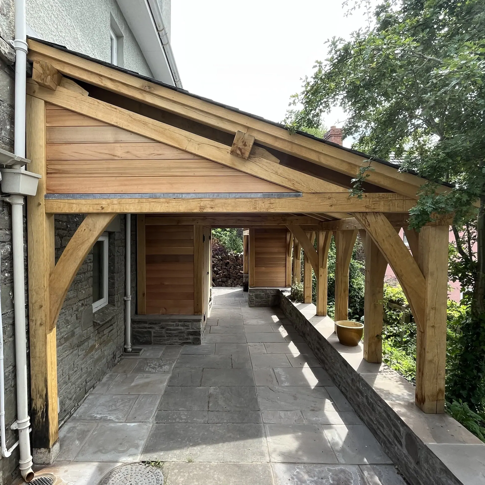 Oak frame loggia and cedar-clad log store beside a house at Crickhowell.