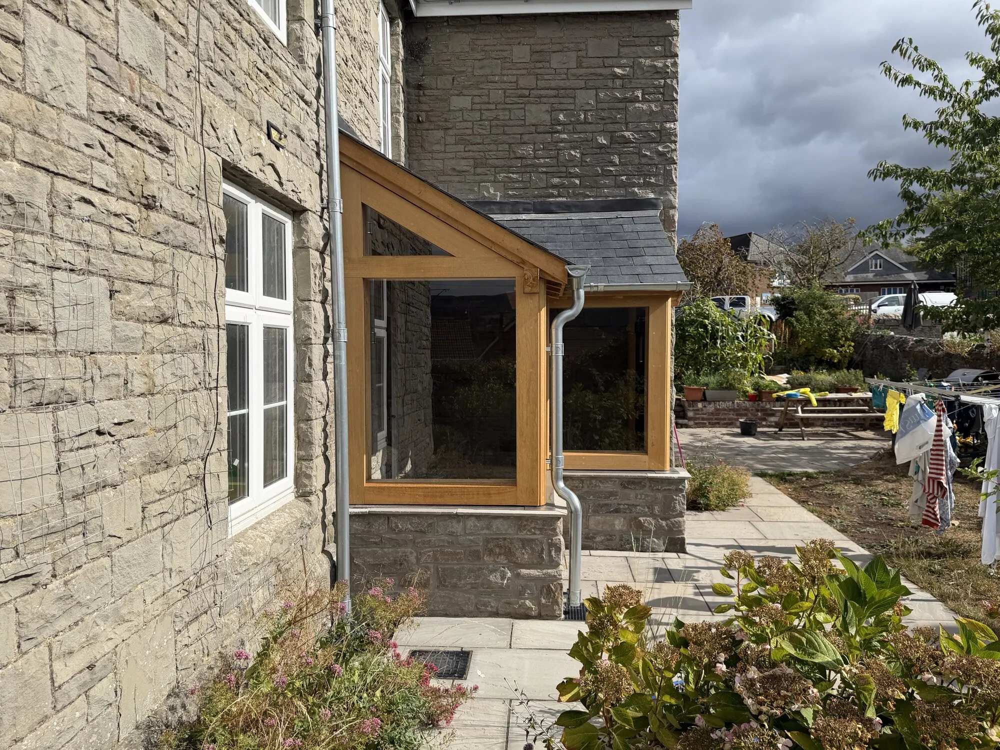 Glazed oak corner porch seen from the garden of a stone house in Crickhowell