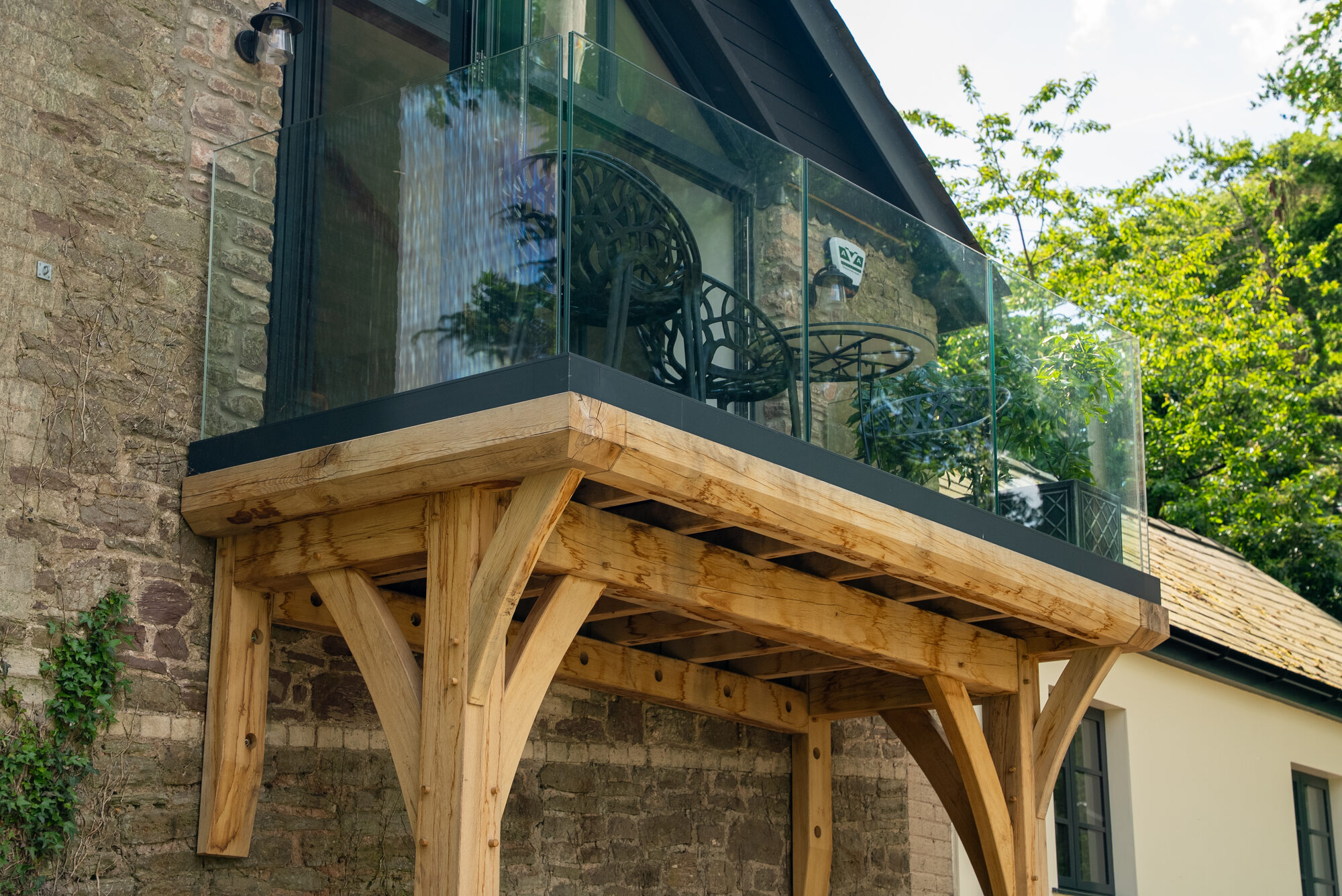 Oak balcony at Llangybi with a frameless glass balustrade fixed at the base