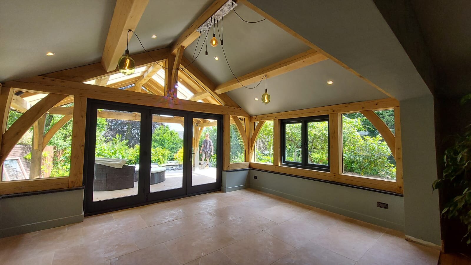 The Pontypool garden room under three king post trusses, with glazing on two sides looking out to the covered outdoor area