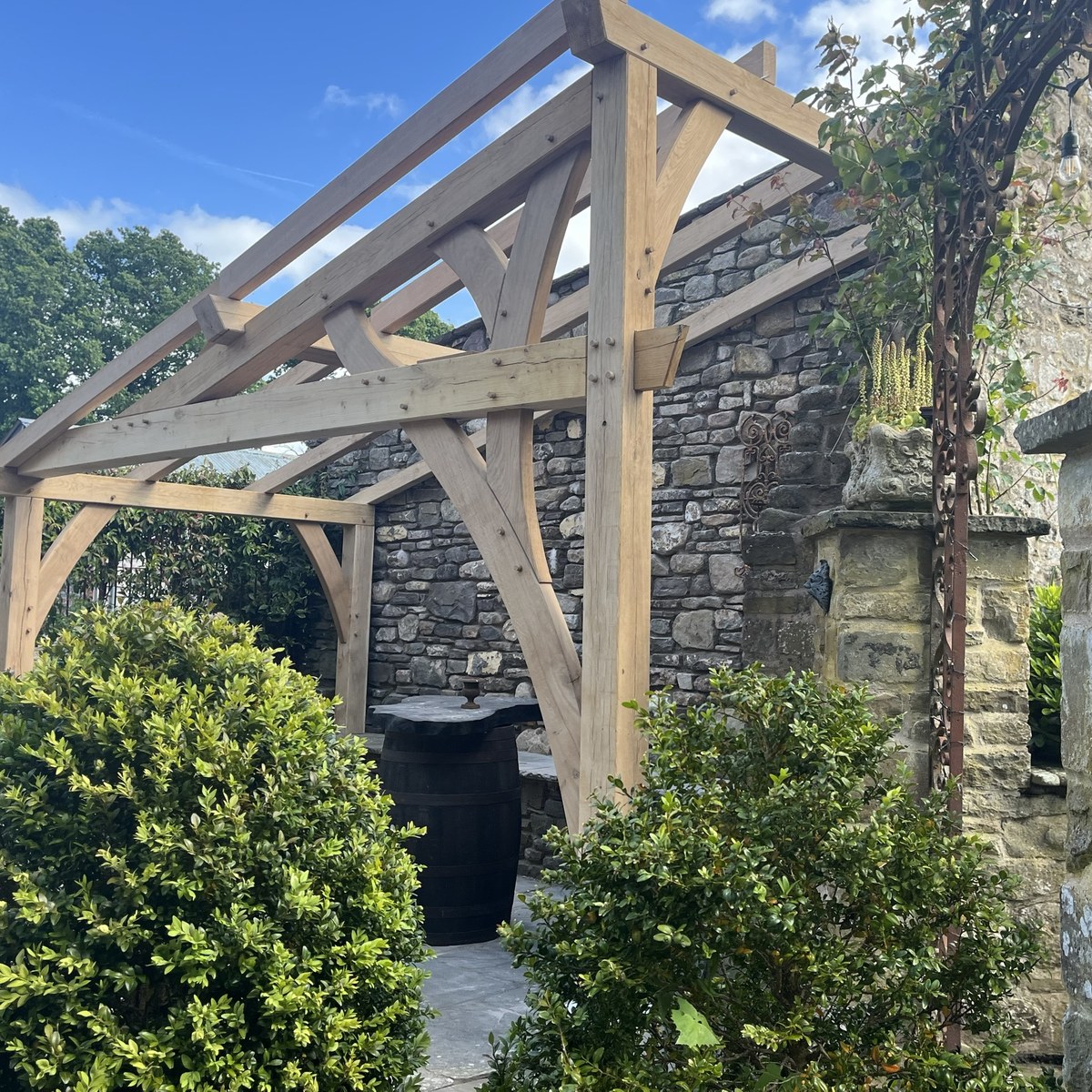Oak shelter frame with oak branch bracing in the stone courtyard at Duffryn Mawr, Gilwern
