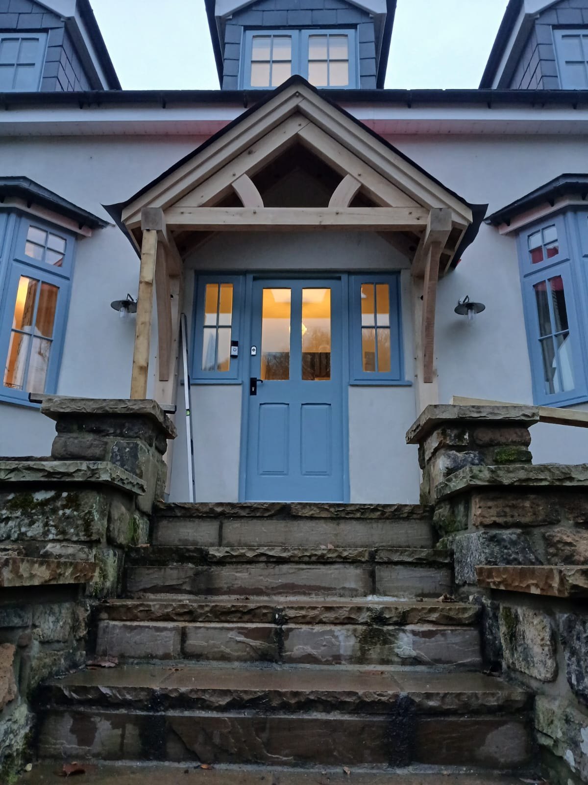Oak gable porch lit at dusk above stone steps at Tintern