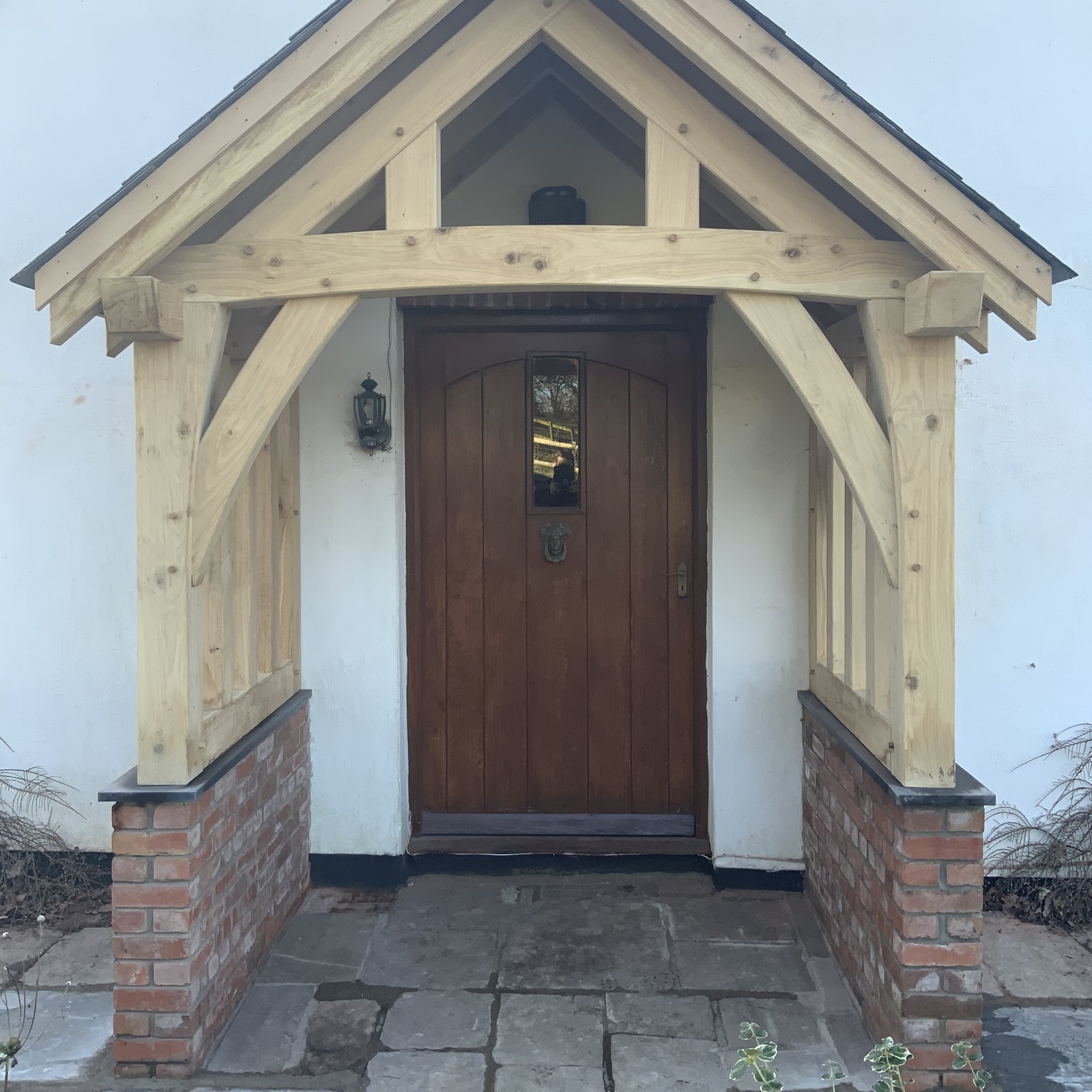 Oak gable porch on brick plinths around a dark wooden front door