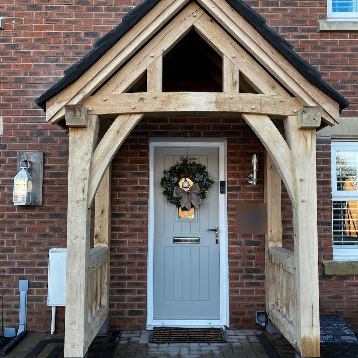 Oak gable porch with curved braces over a light grey front door