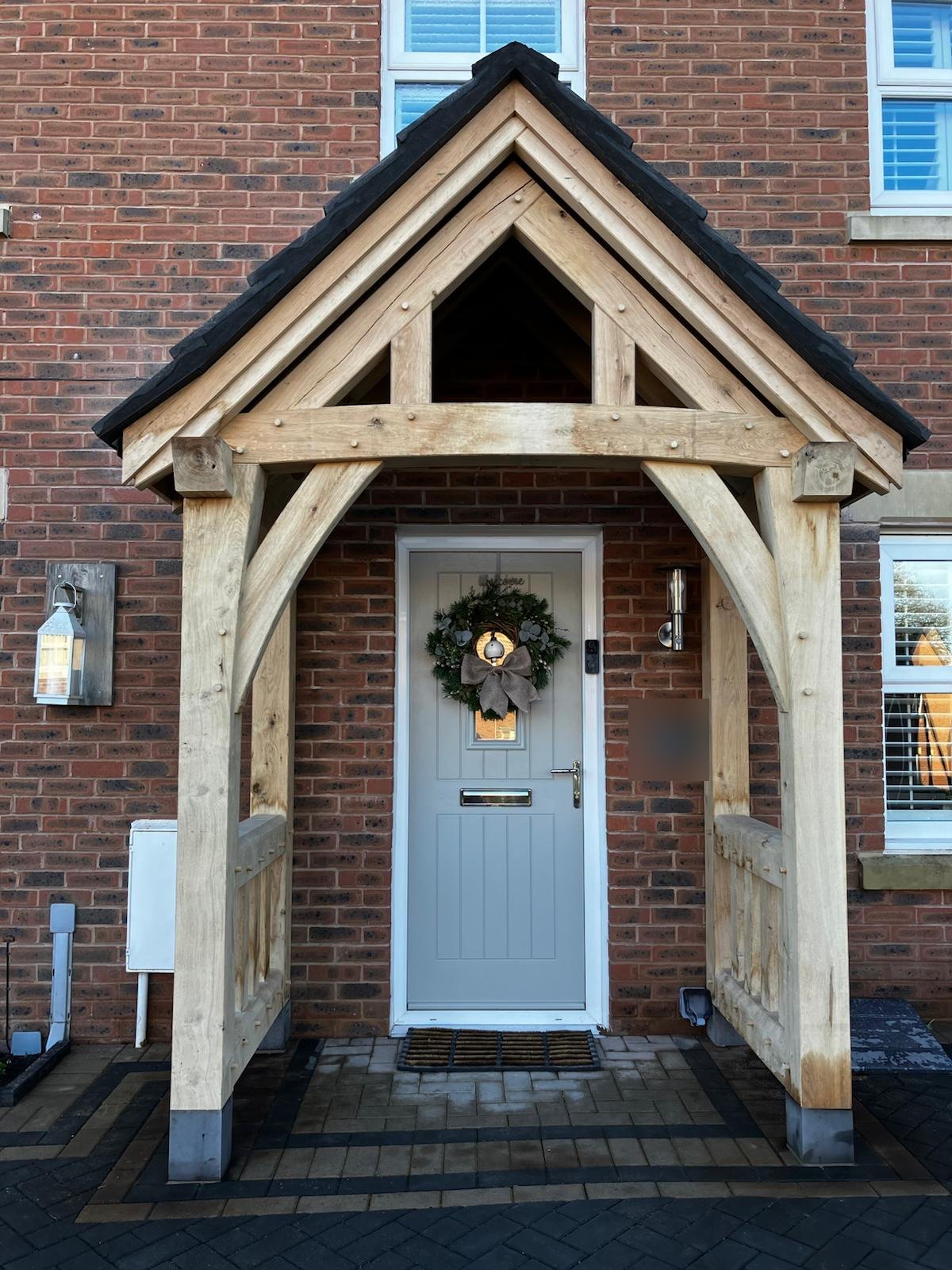 Oak porch with curved braces and oak balustrade sides, seen straight on, on a red brick house at Pontllanfraith