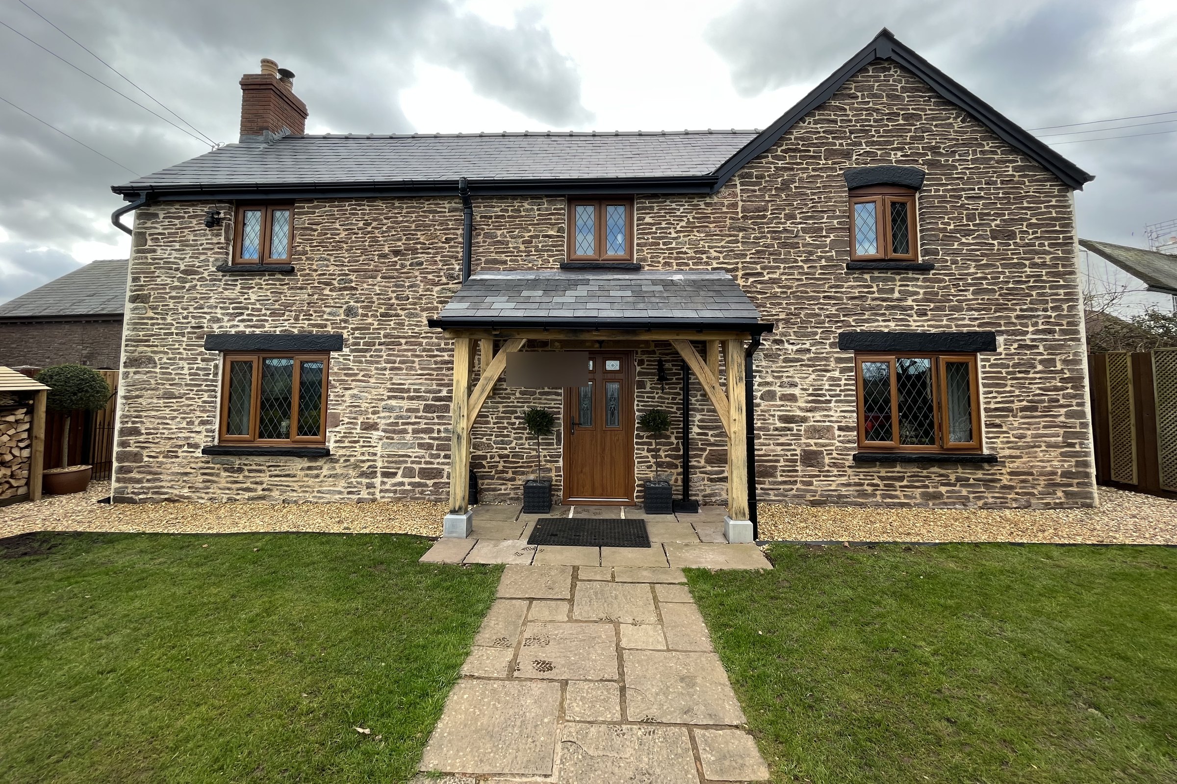 Oak lean-to porch with a slate roof on a stone cottage at Newcastle, near Monmouth