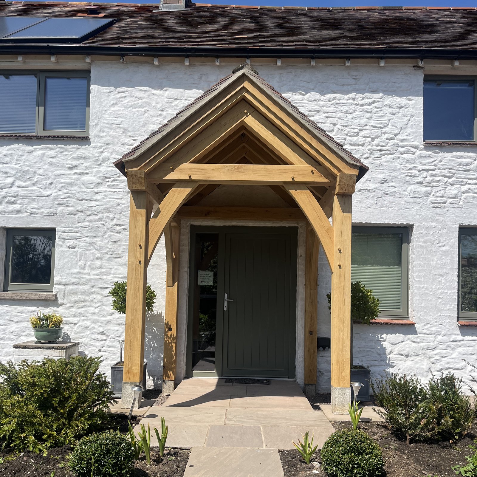 Open oak gable porch on four posts in front of a green front door