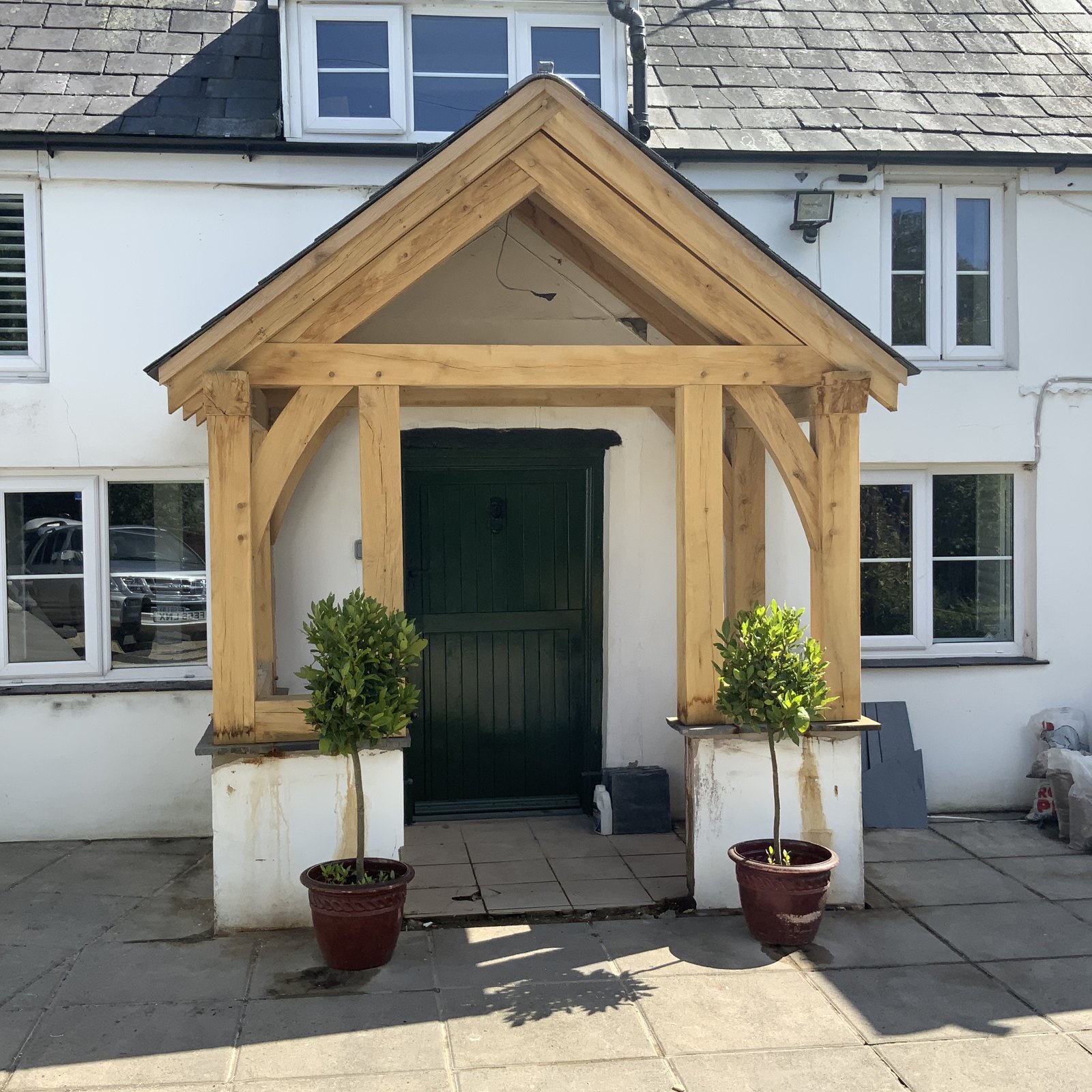 Oak gable porch on rendered plinth walls over a dark green front door