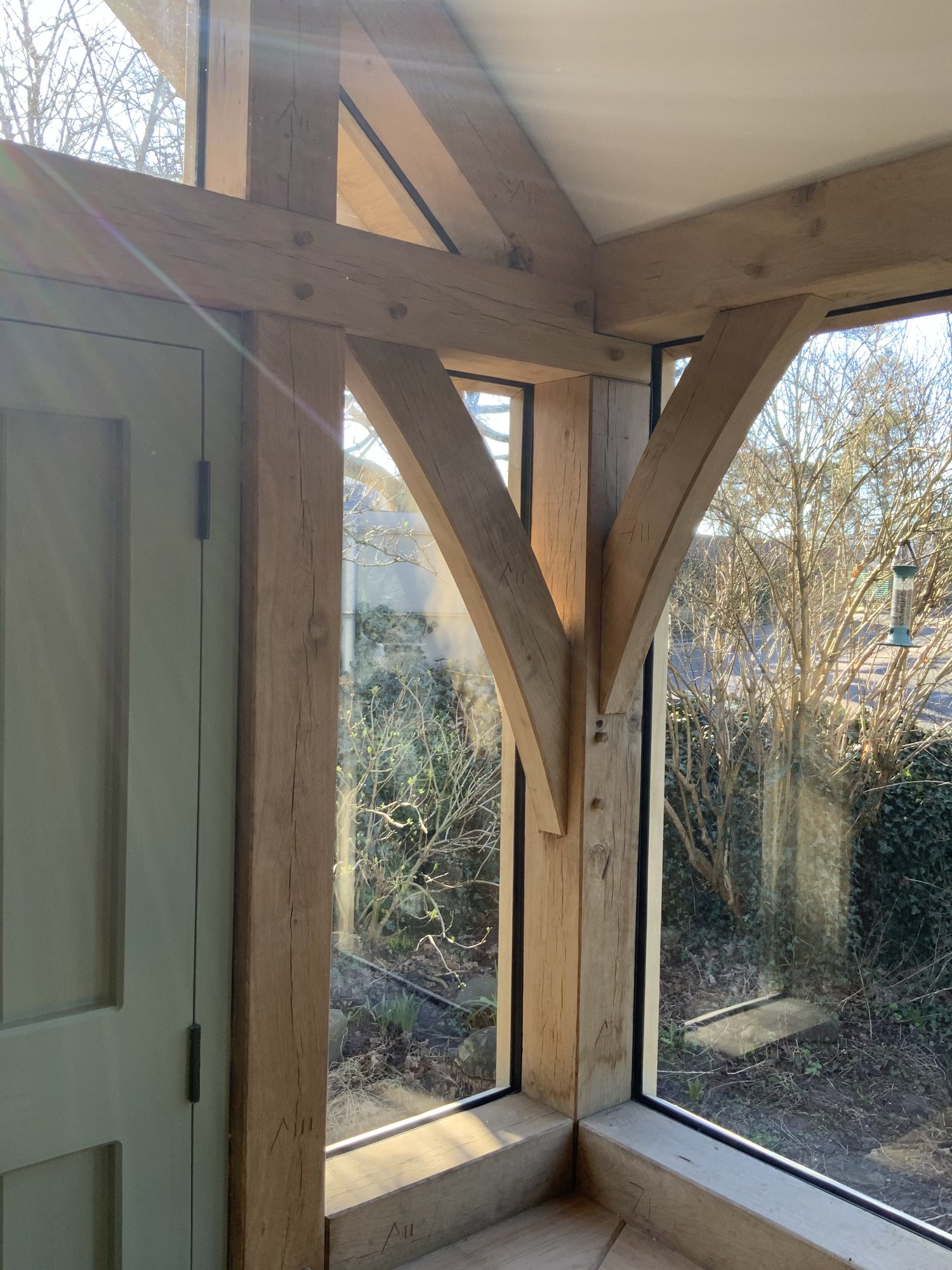 A curved oak brace and the glazing around it, inside a glazed oak gable porch at Llanvihangel Crucorney