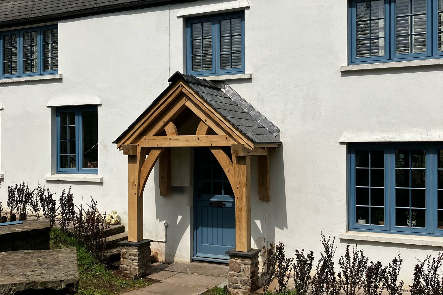 Oak gable porch with a slate roof on a whitewashed farmhouse