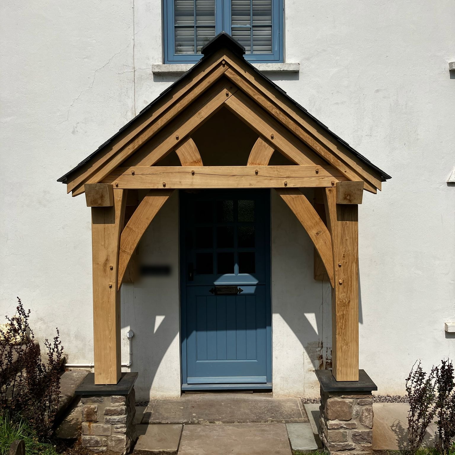 Oak gable porch on stone plinths over a blue front door